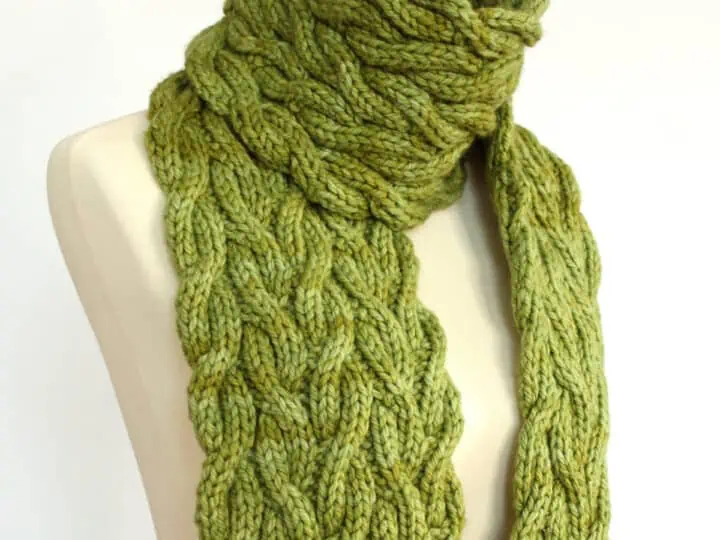 Meadow Vine Reversible Cable Scarf in green yarn displayed on mannequin.