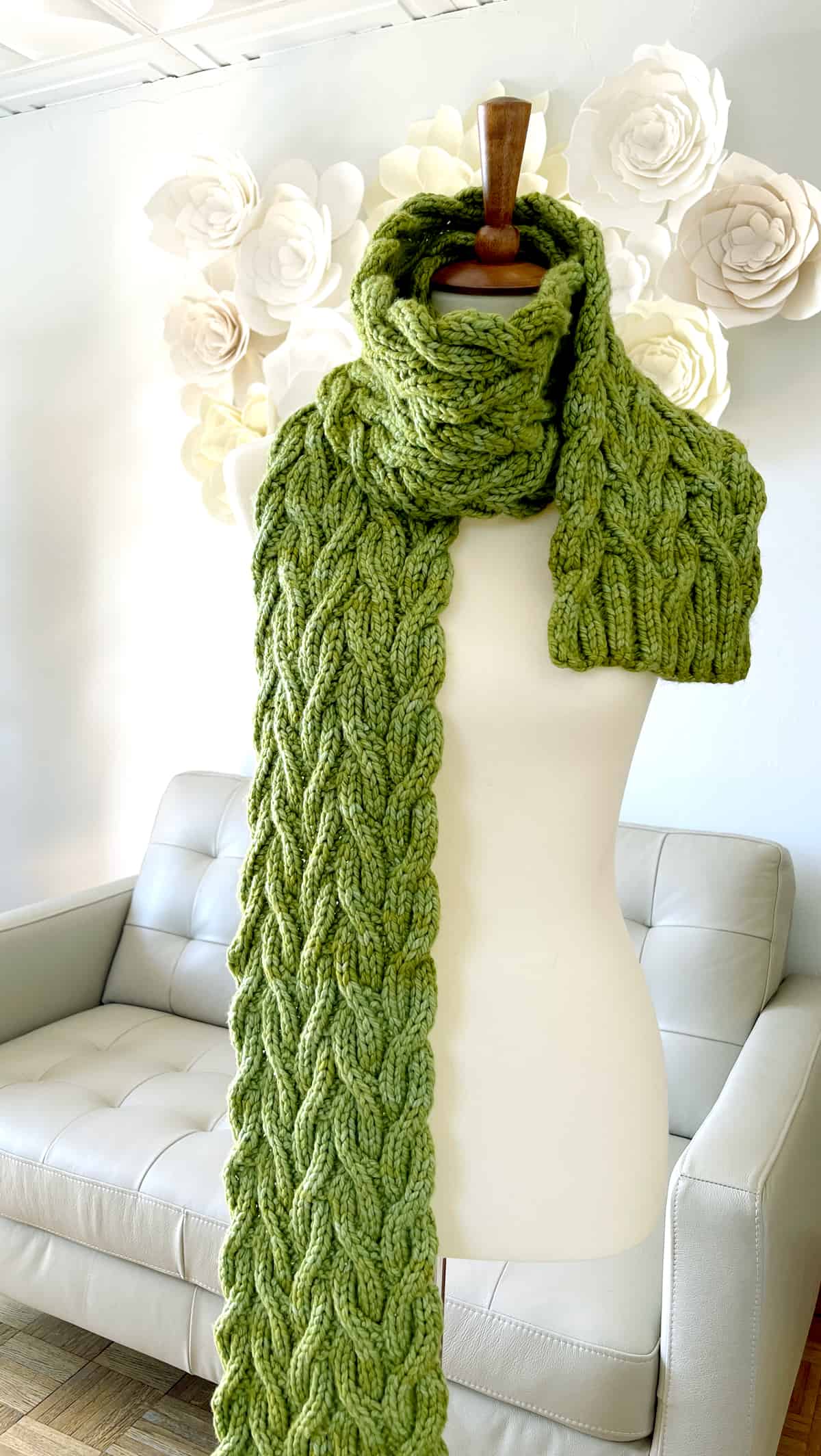 Green reversible cable knitted scarf on mannequin at Studio Knit.
