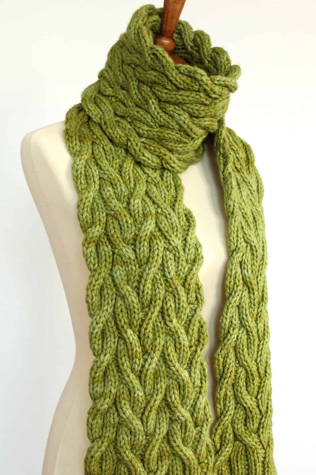 Meadow Vine Reversible Cable Scarf in green yarn displayed on mannequin.