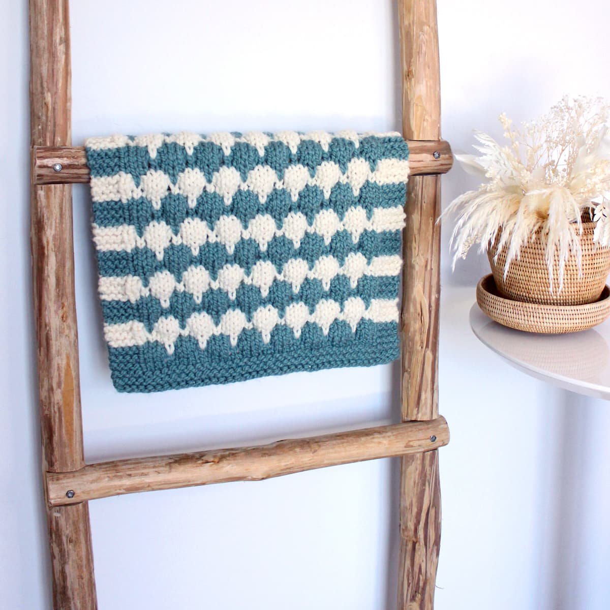 Chunky bubble stitch blanket displayed on rustic ladder.