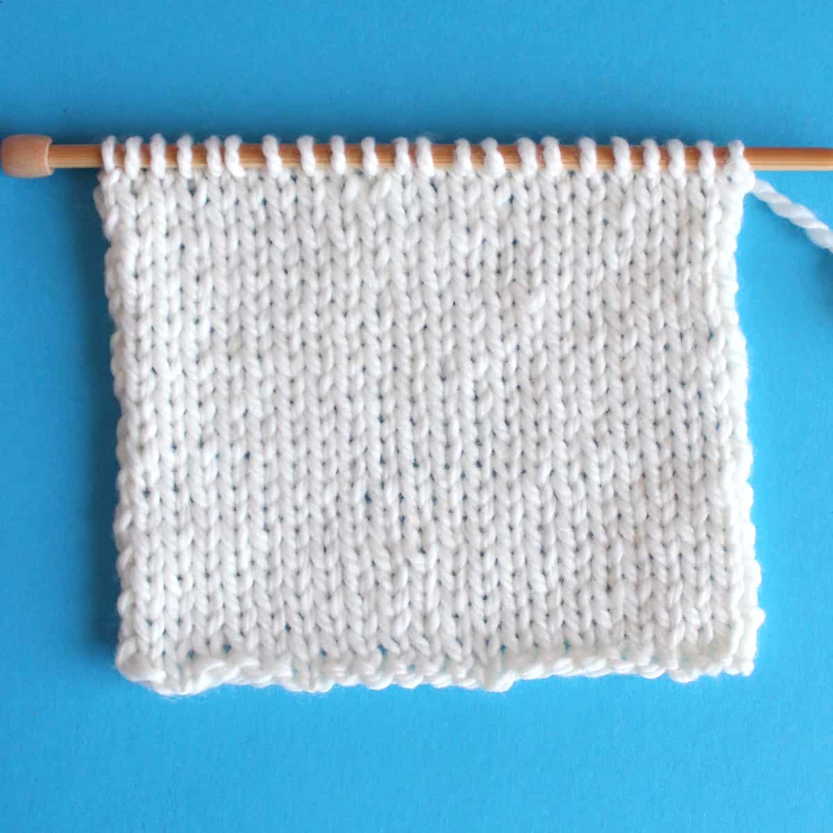 Stockinette stitch knitted flat on straight knitting needles in white color yarn.