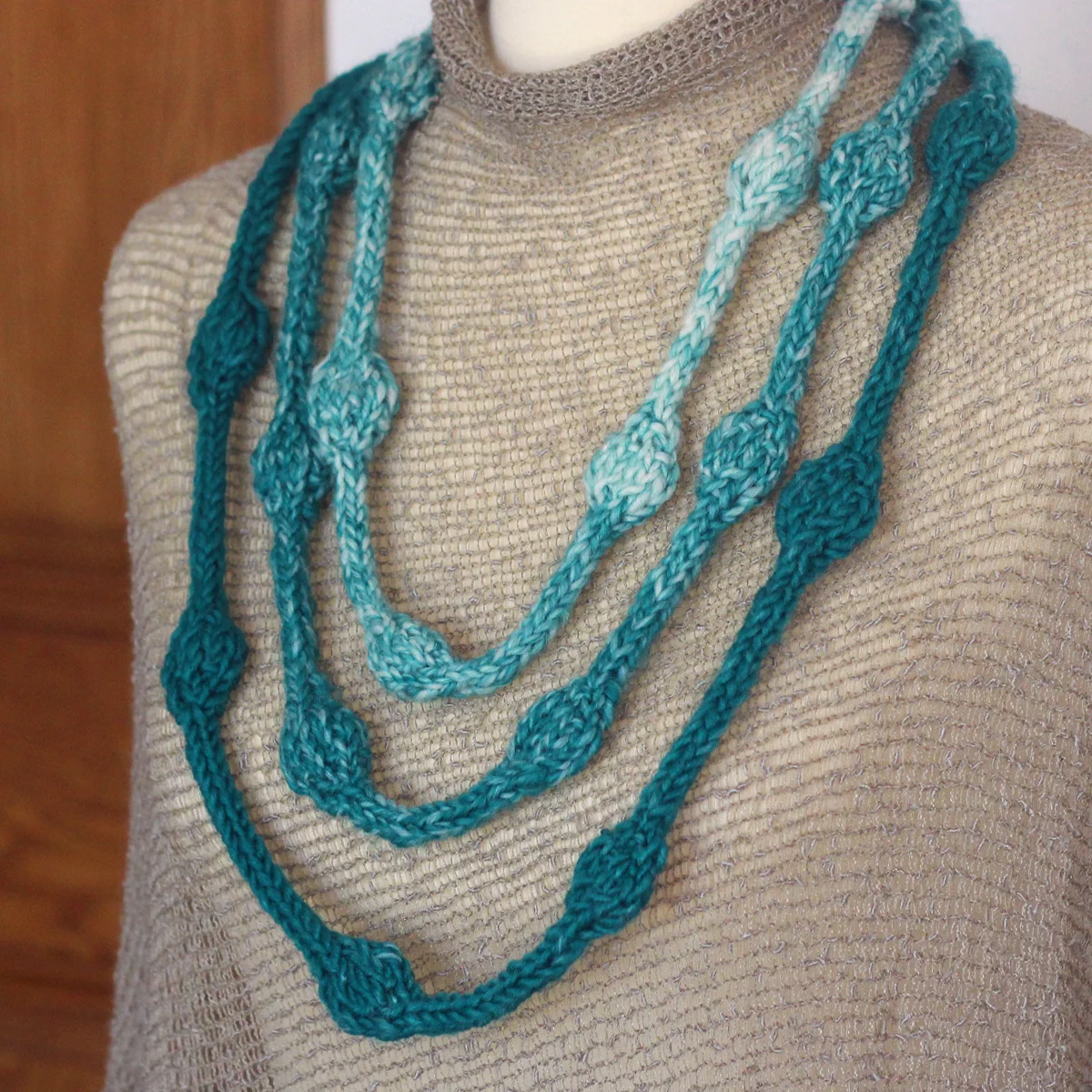 Close-up of a Necklace with Beaded Texture knitted in blue and white yarn colors worn on a torso.