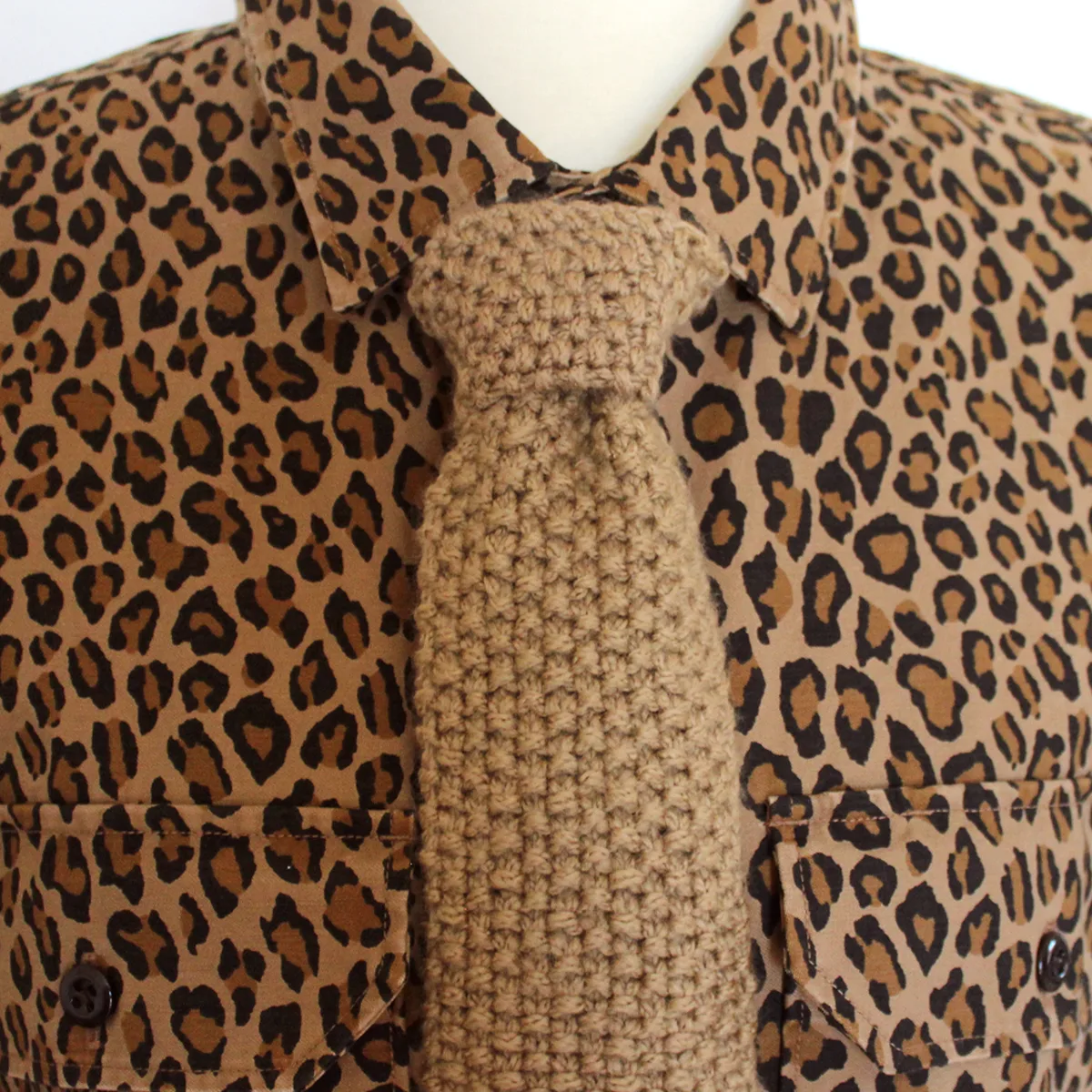 Seed stitch knitted necktie worn on men's leopard print button-down shirt.