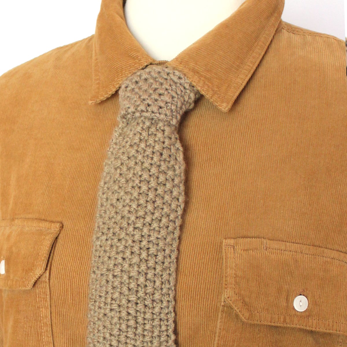 Seed stitch knitted necktie worn on tan men's corderoy shirt.