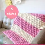 Chunky Bubble Blanket knitting pattern by studio knit in 6 sizes with afghan on couch in pink and white yarn colors.
