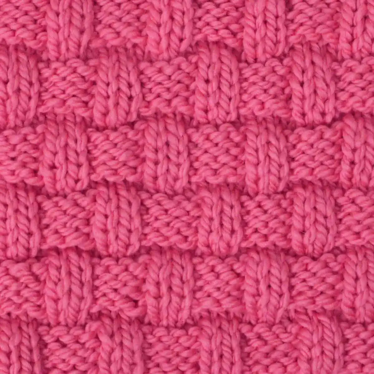 Basket Weave stitch pattern on knitting needle in pink color yarn.