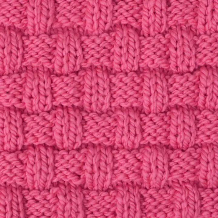 Basket Weave stitch pattern on knitting needle in pink color yarn.