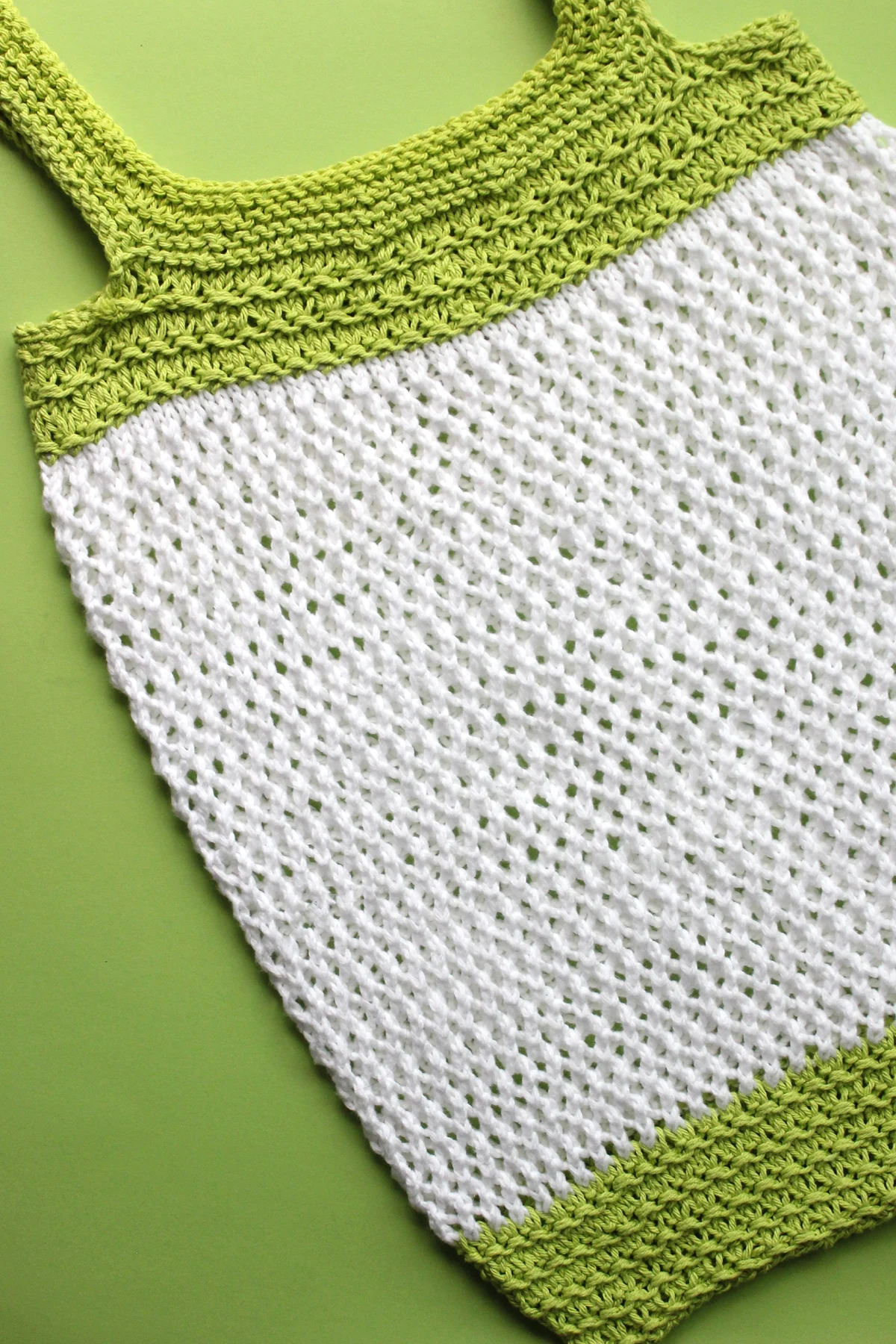 Mesh market bag knitted in green and white yarn colors.
