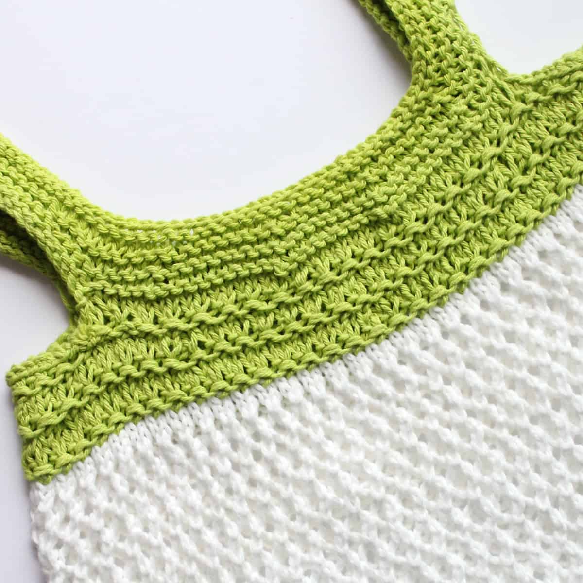 Top of mesh market bag knitted in green and white yarn colors.