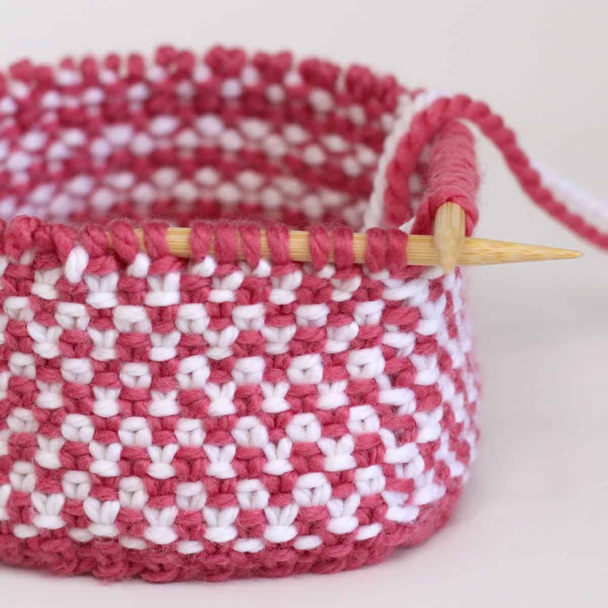 Linen stitch pattern knitted in the round on circular needles in pink and white yarn colors.
