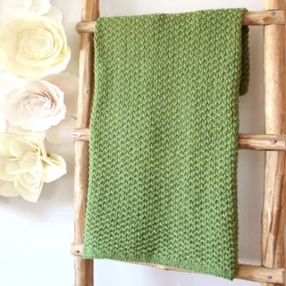 Wooden ladder with Moss Landing knitted blanket by Studio Knit in green yarn color.
