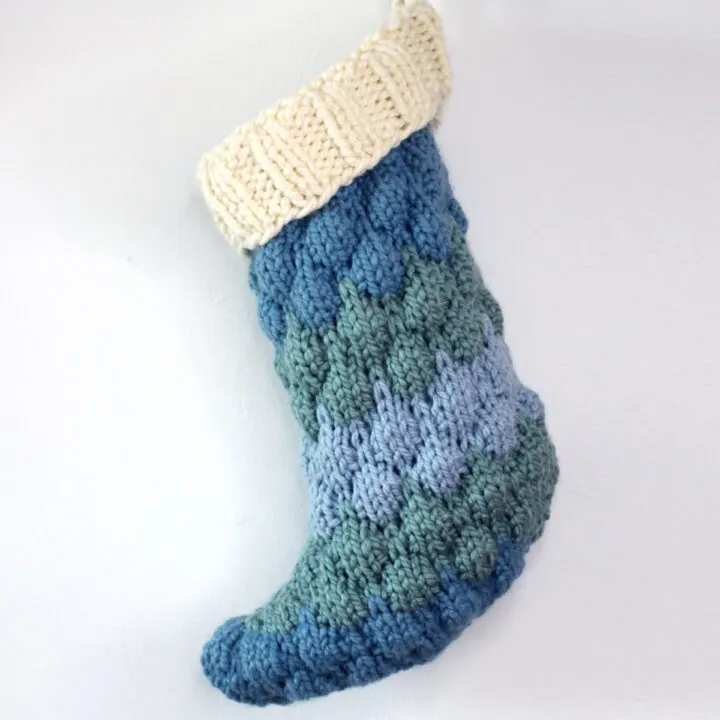 Knitted Bubble Stocking with three shades of blue yarn and a cream color cuff.