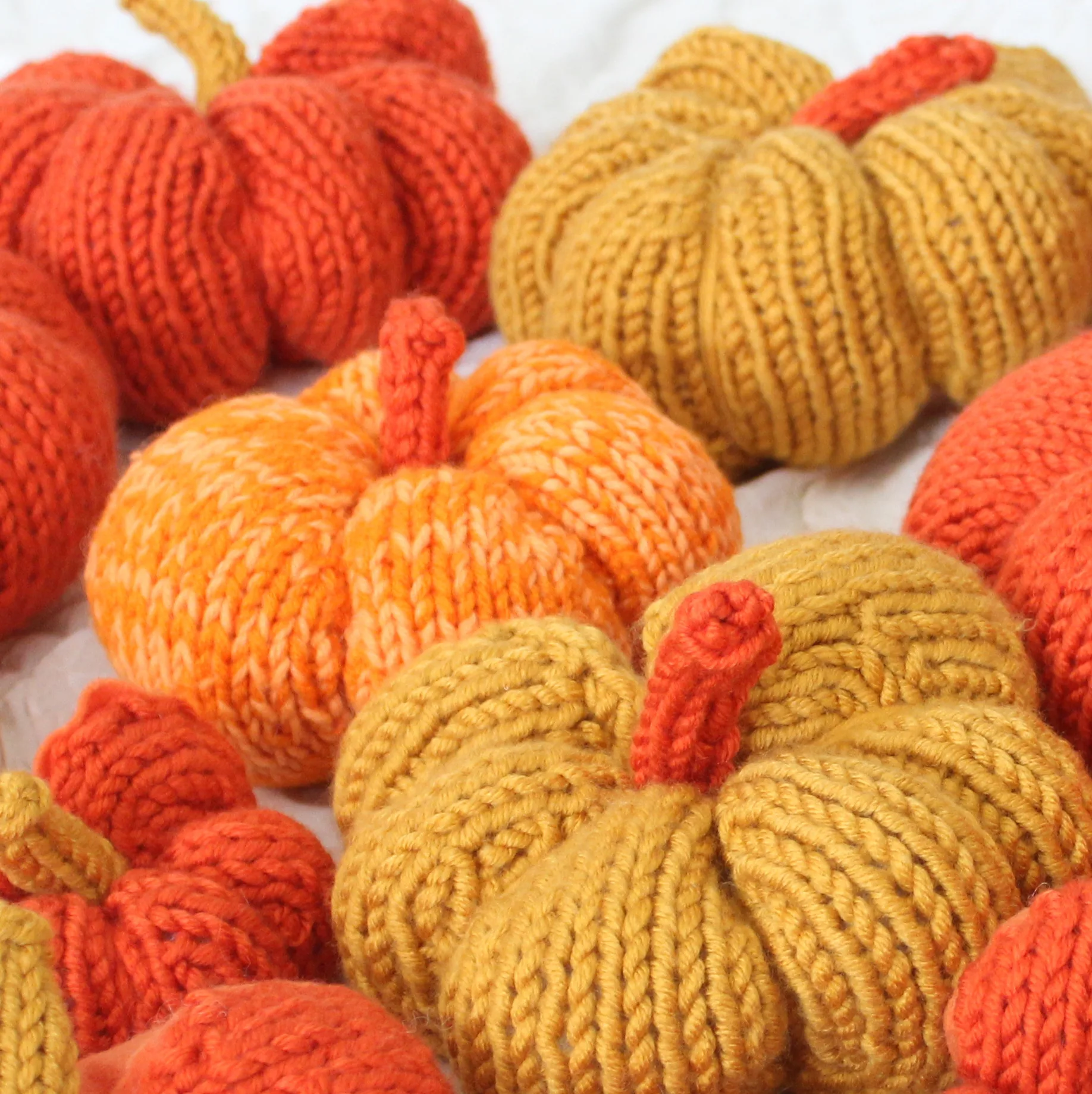 Knitted pumpkin softies in yellow and orange yarn colors.