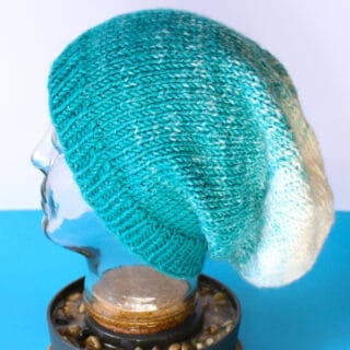 Knitted Slouchy Beanie on mannequin head in blue to white ombre yarn colors.