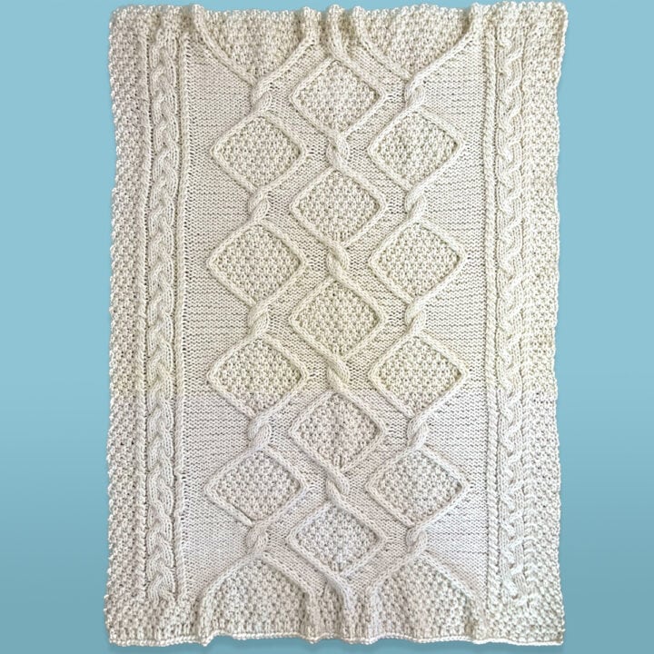 Full sized cable knit throw in the Diamond Heights pattern by Studio Knit.