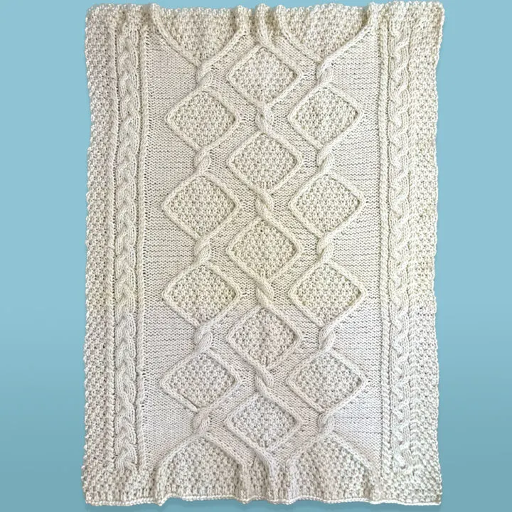 Full sized cable knit throw in the Diamond Heights pattern by Studio Knit.
