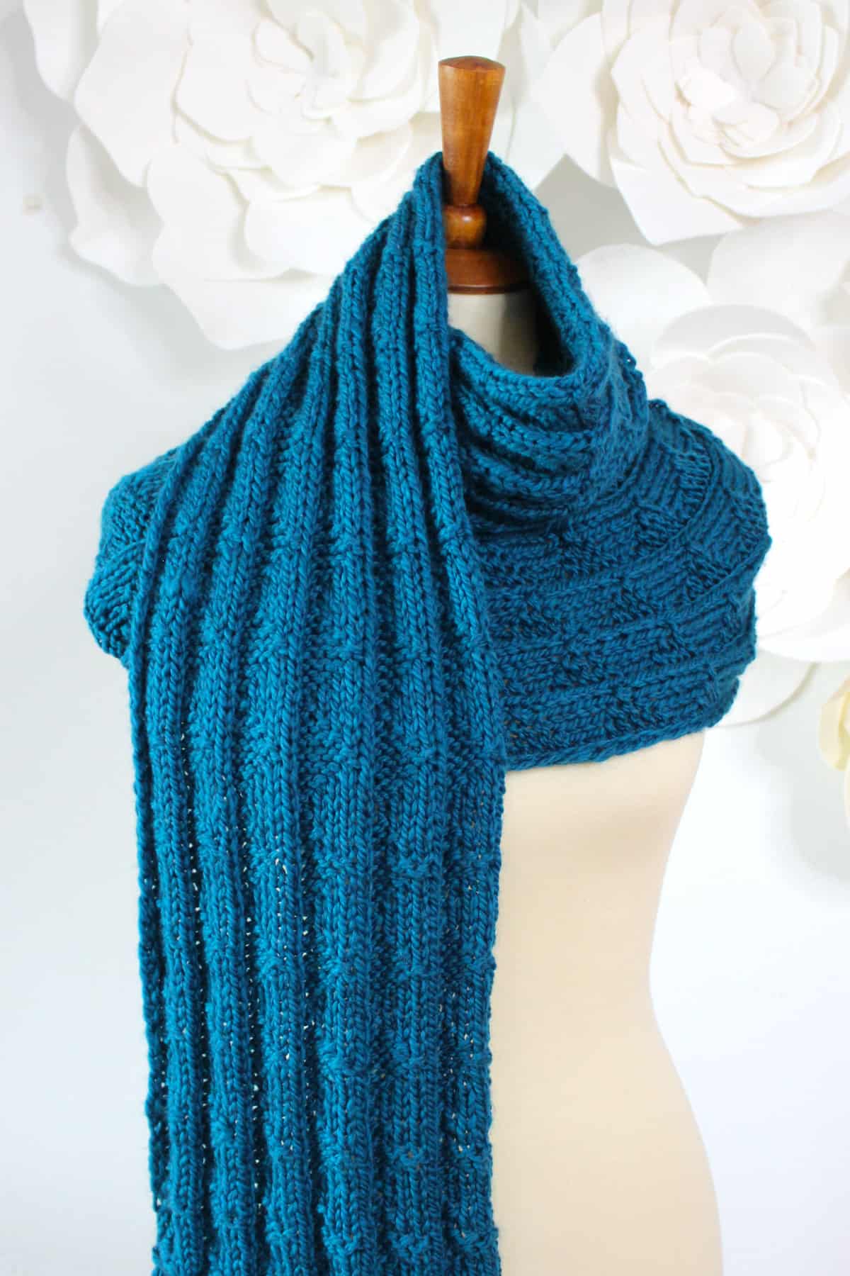 Pennant Pleating knitted scarf wrapped on mannequin in blue color yarn.