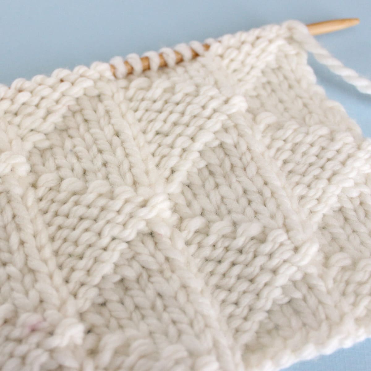 Pennant Pleating stitch in white color yarn on knitting needle.
