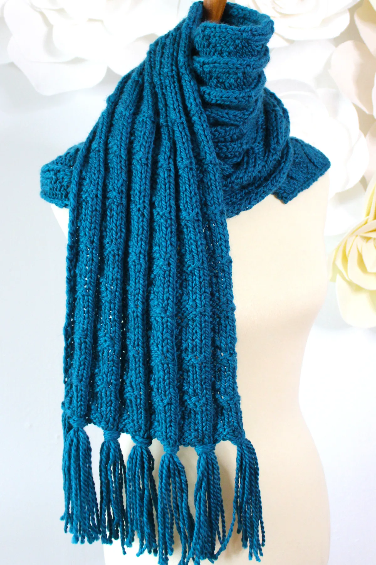 Pennant Pleating knitted scarf with fringe wrapped in blue color yarn.