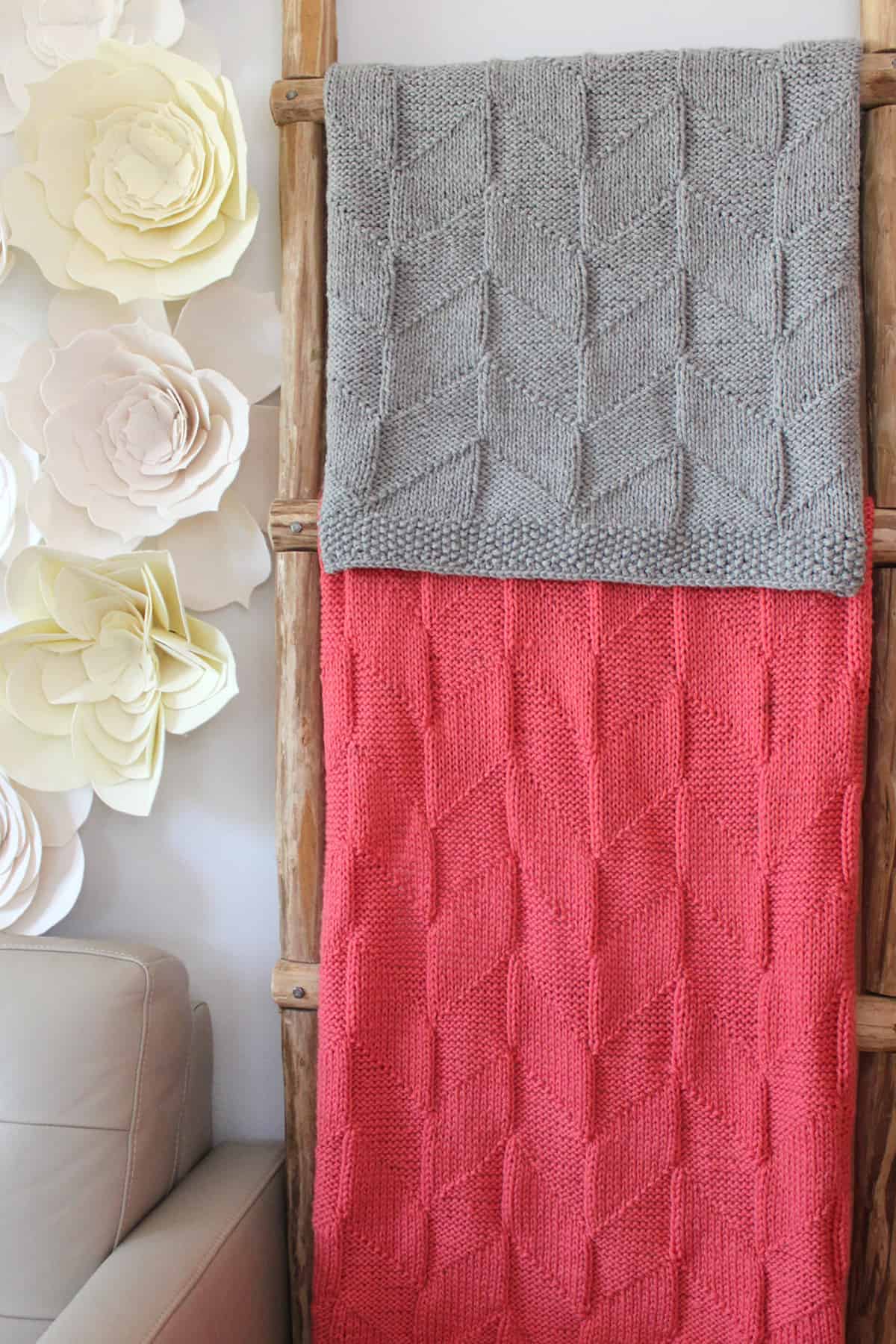 Point Reyes Blanket in parallelogram stitch designed by Studio Knit in grey and peach colored yarn displayed on ladder.