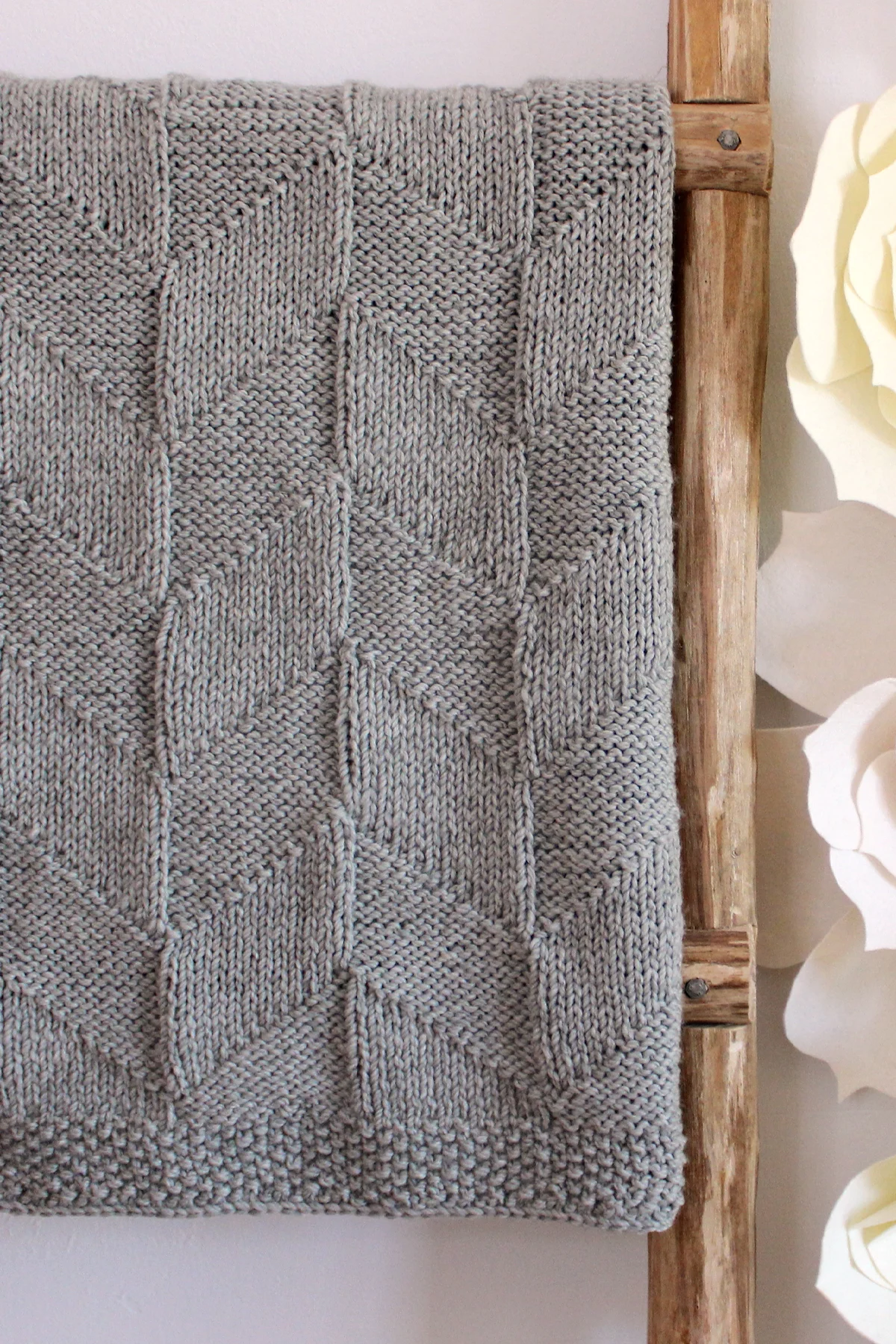 Point Reyes Blanket designed by Studio Knit in grey colored yarn displayed on ladder.