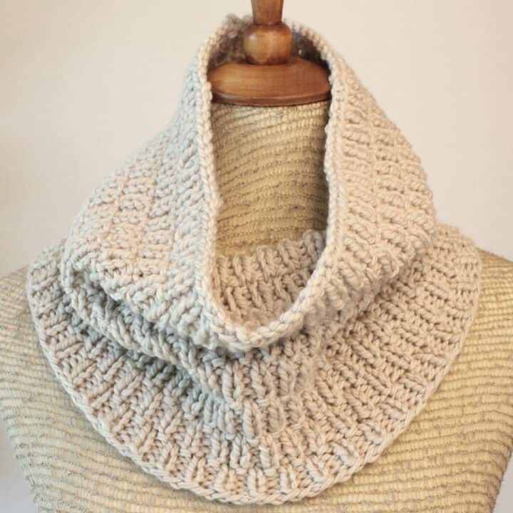 Long Raindrops Cowl Scarf knitted with beige color yarn displayed on mannequin.