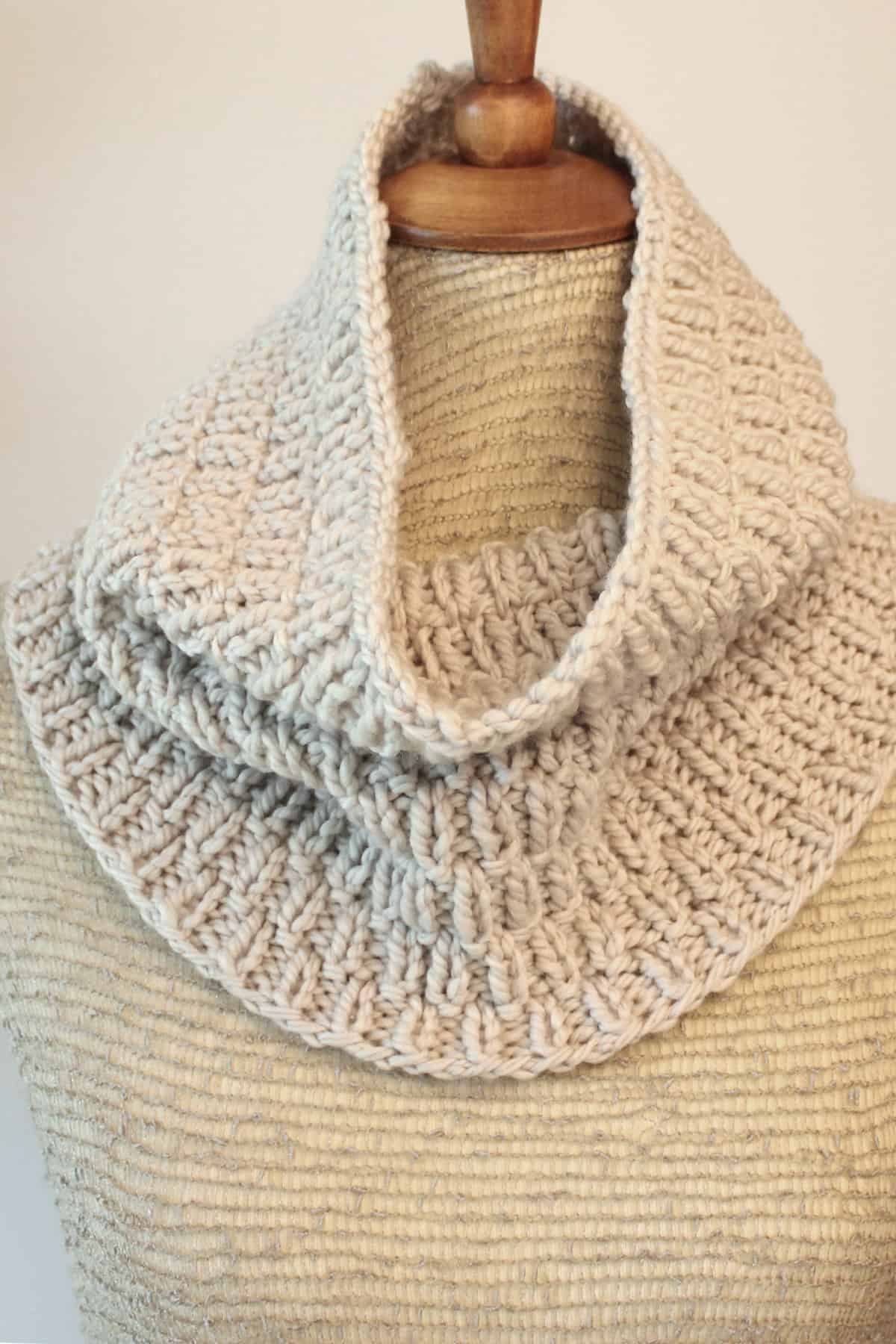 Short Cowl Scarf knit in long raindrops knit stitch pattern with beige color yarn displayed on mannequin.