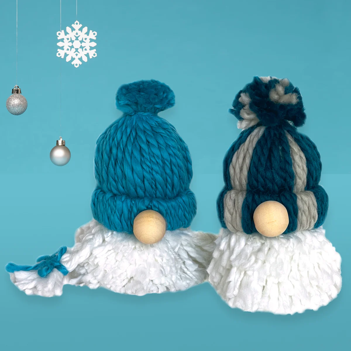 Two yarn gnome ornaments made with pom poms and a wooden nose in blue and white colors.