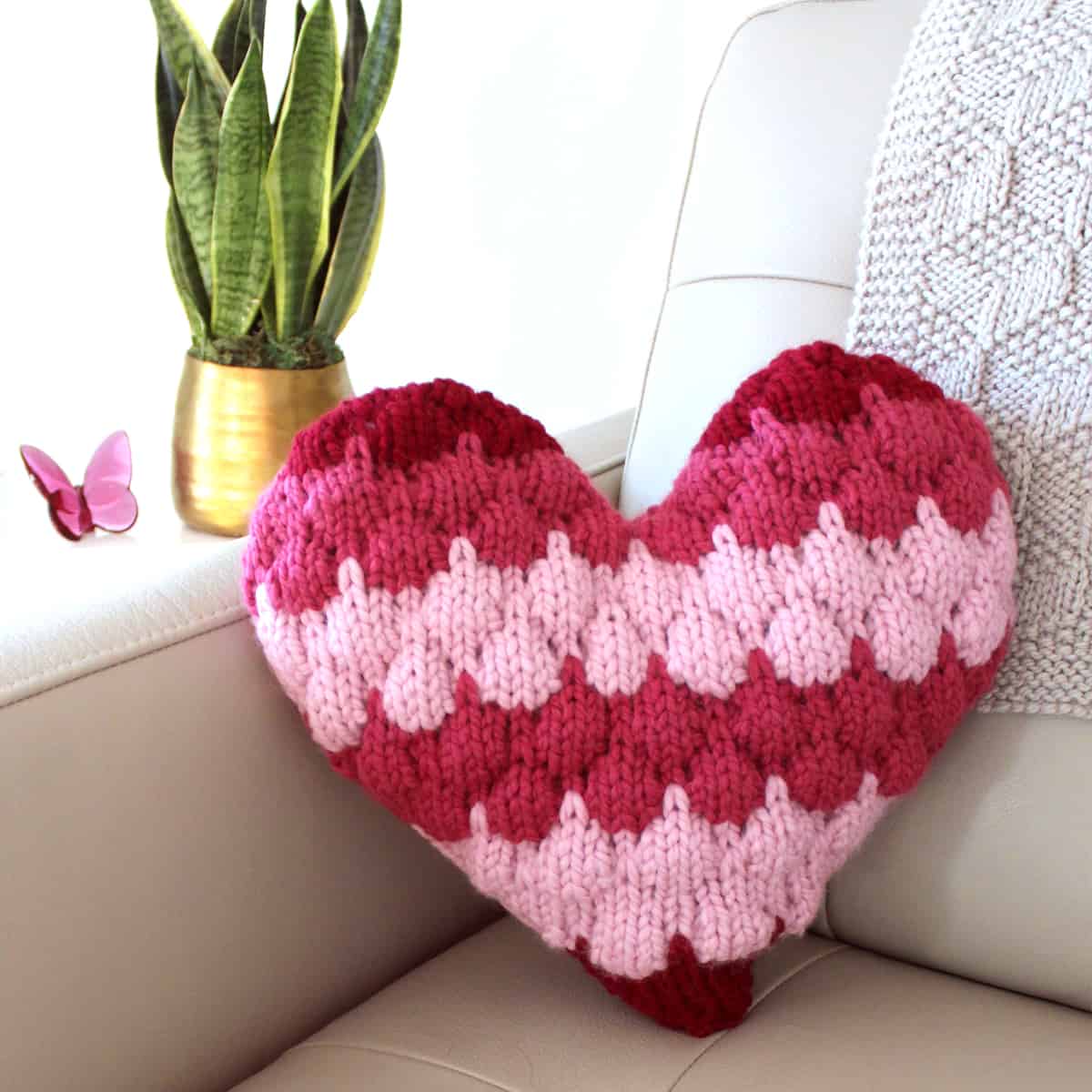 Bubble Stitch Heart throw pillow resting on a couch.