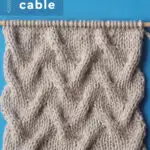 Sand Drift Cable stitch on wooden bamboo knitting needle with beige colored yarn by Studio Knit.