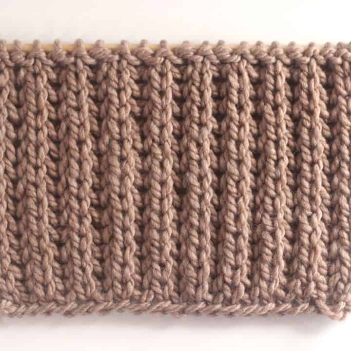 Fisherman's Rib knit stitch pattern in on a wooden bamboo knitting needle with brown yarn color.