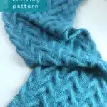 Long scarf in Sand Cable knit stitch pattern knitted flat with a straight knitting needle in blue yarn color.