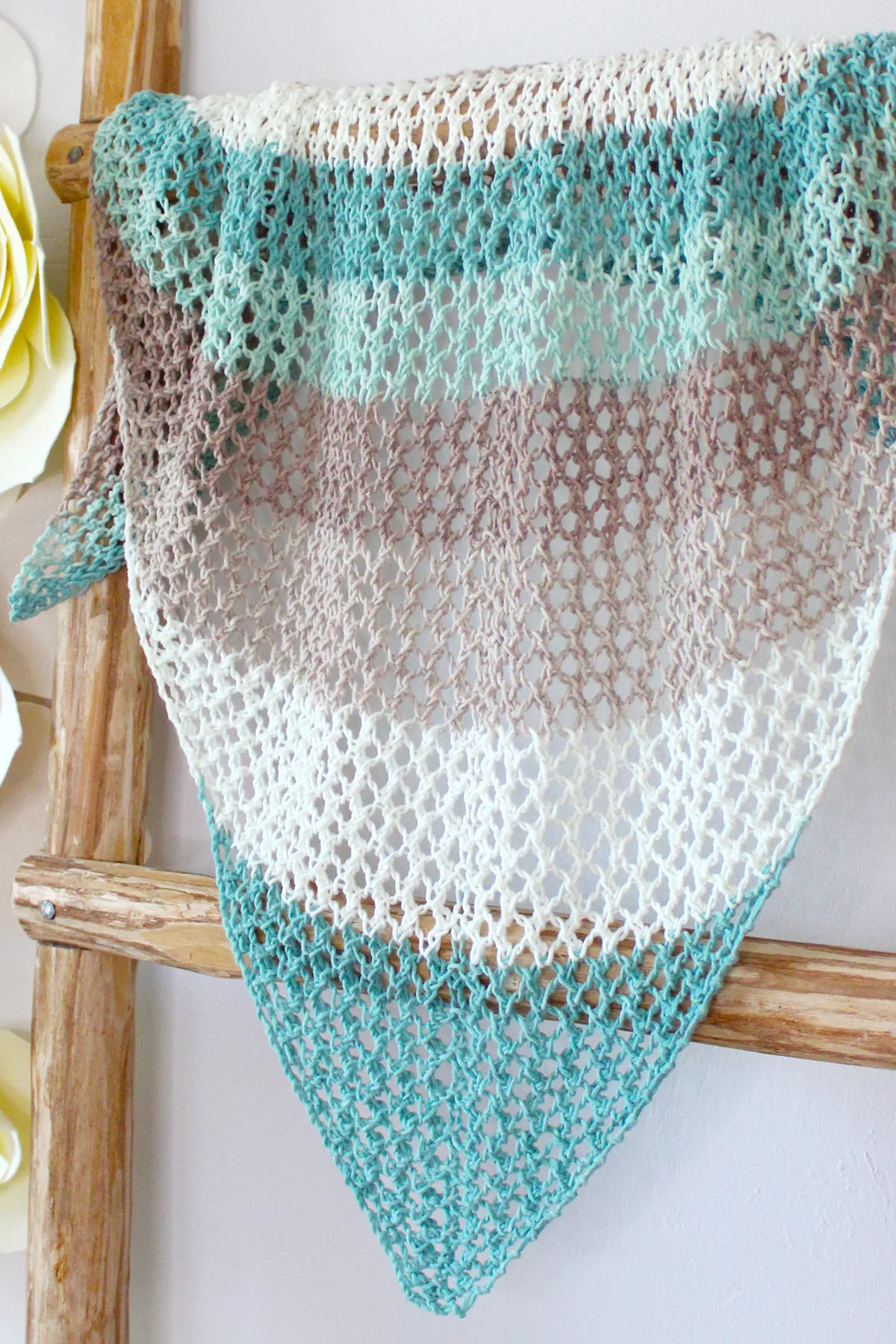 Mesh knitted shawl in multicolors displayed on a wooden blanket ladder.
