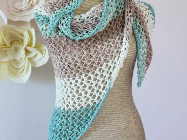 Knitted mesh shawl in displayed on a mannequin in colors blue, brown, and white.