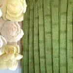 Knitted blanket in bamboo stitch texture in green colored yarn displayed on a wooden ladder.