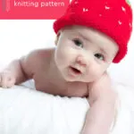 Baby wearing a strawberry knitted hat in red yarn color.