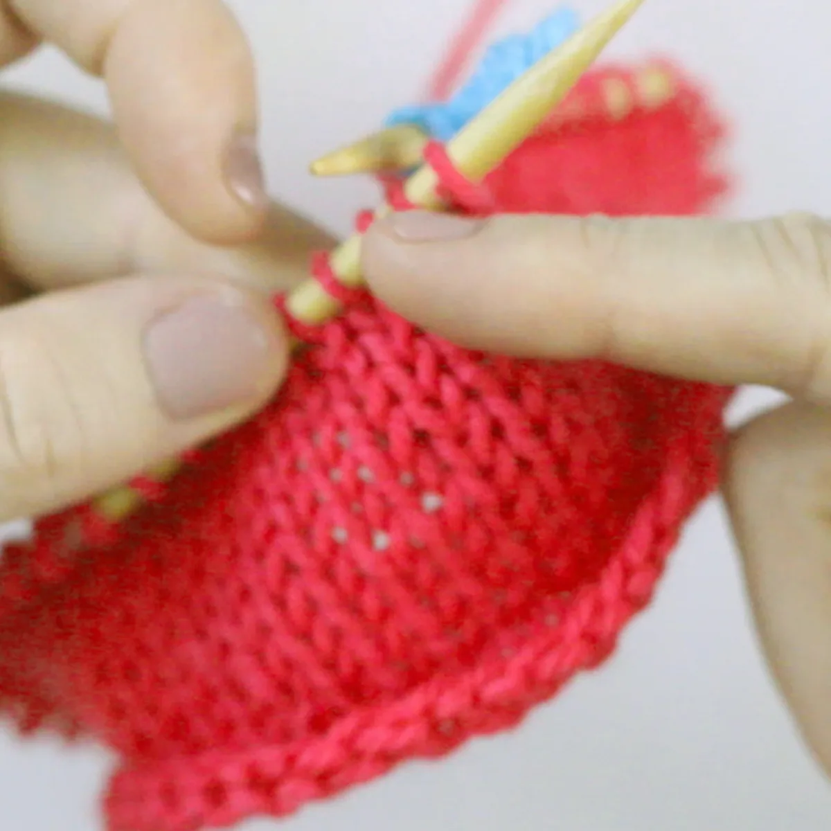 Beginning brim and base area of knitting a strawberry baby hat on circular needles.