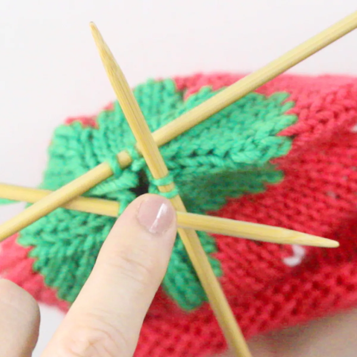 Knitting the topper of the strawberry baby hat with three double pointed needles.