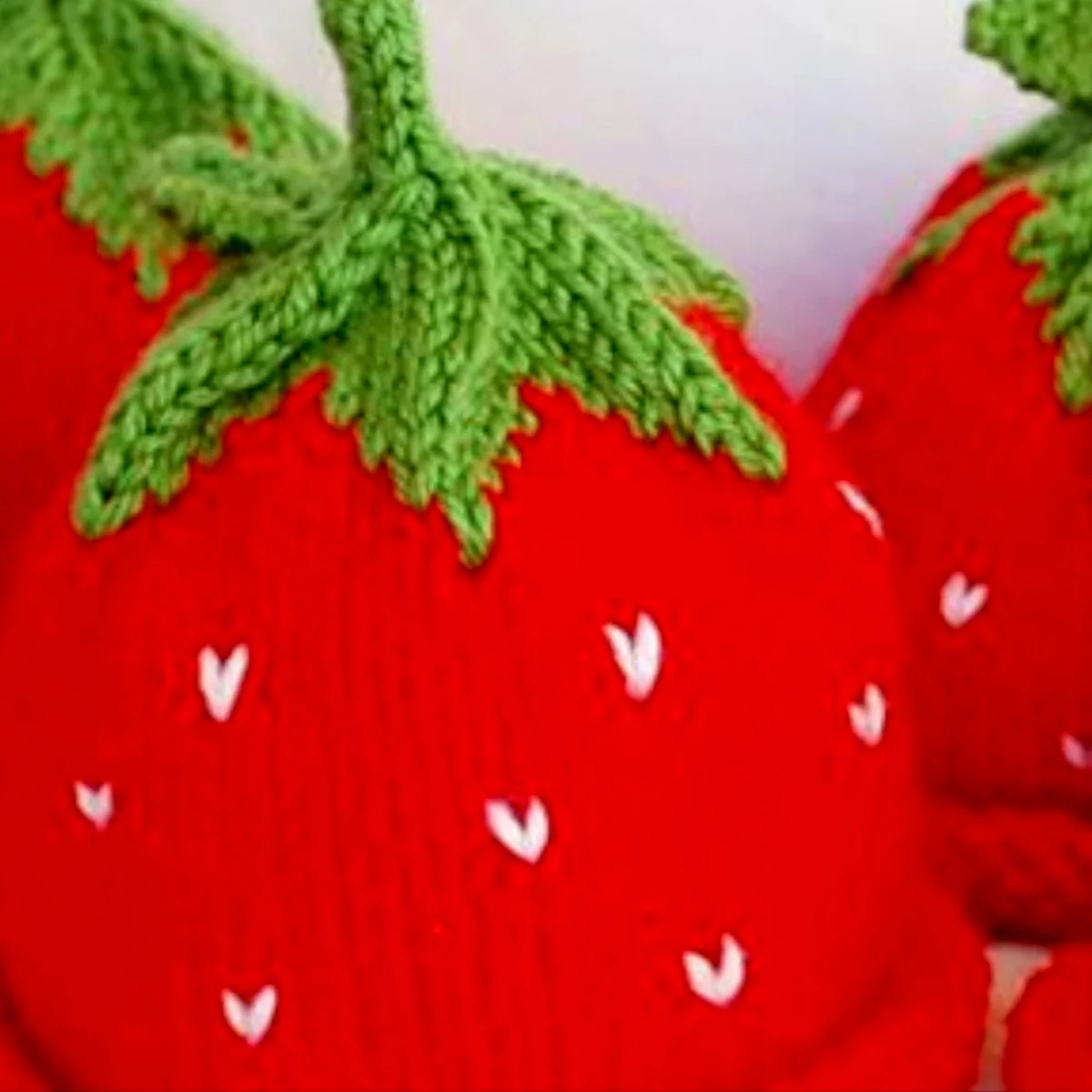 Strawberry Baby Hat knitted with red, green, and white yarn colors.