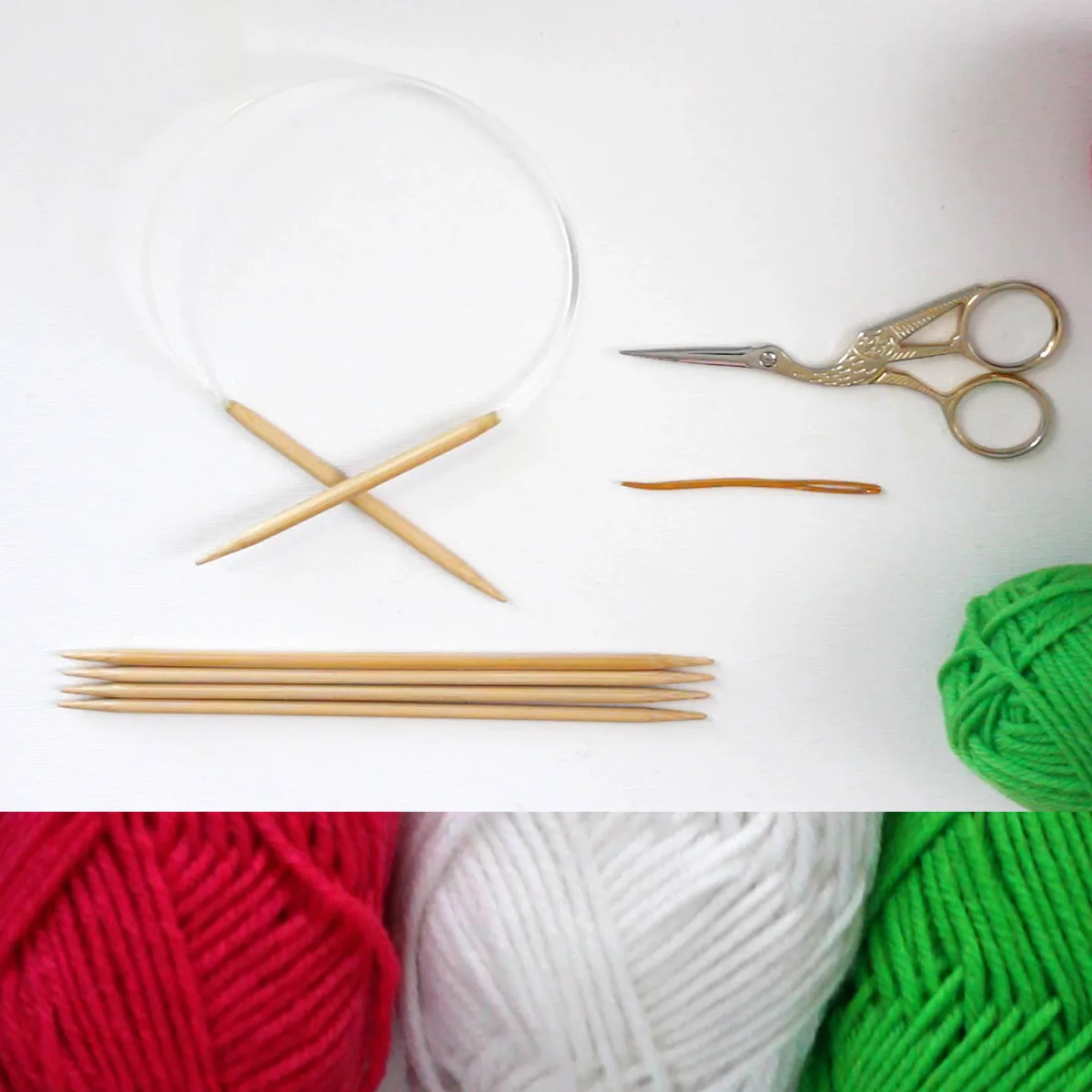 Knitting supplies with circular needle, scissors, double-pointed needles, tapestry needle, and yarn in colors red, white, and green.