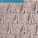 The Eiffel Tower knitting pattern in gray colored yarn on a knitting needle by Studio Knit.