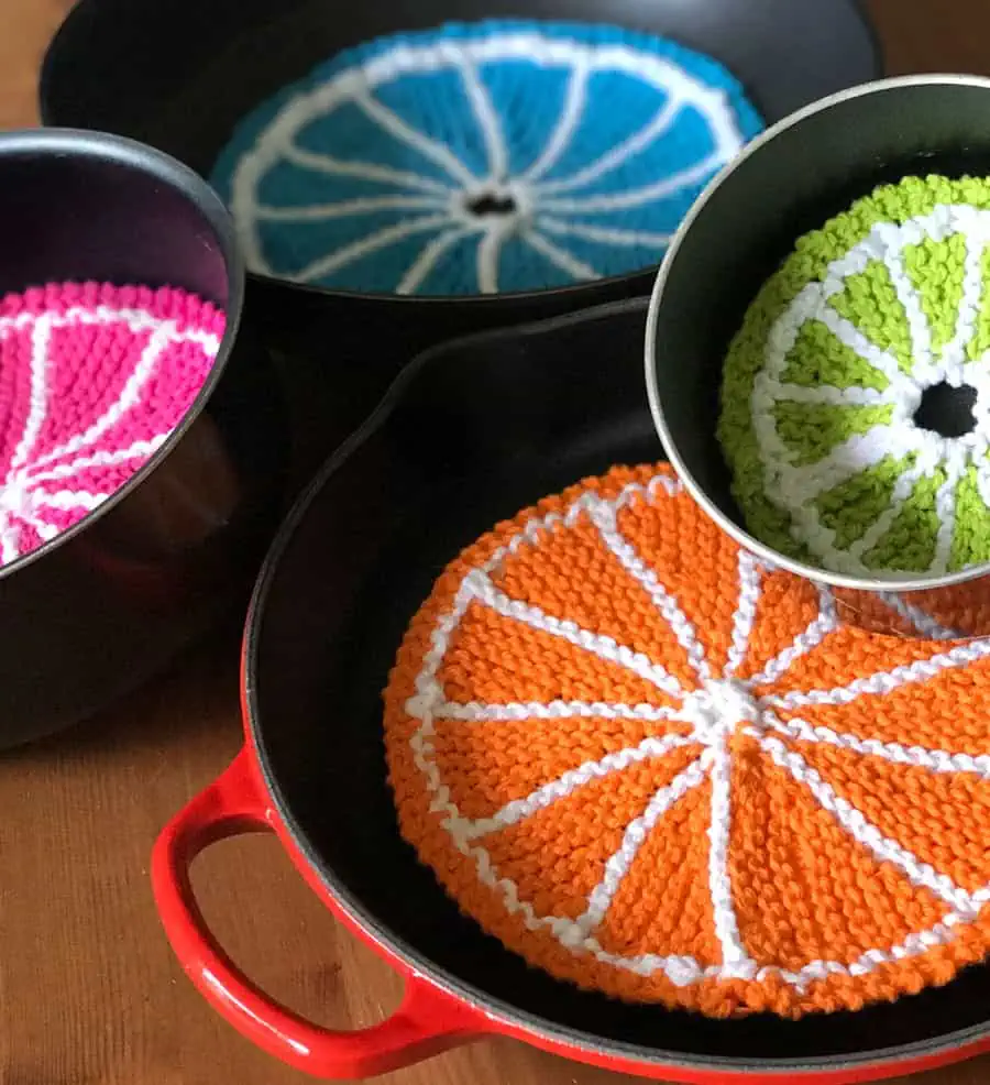 Knitted fruit slice dishcloths within kitchen skillets, pans, and pots as protectors.