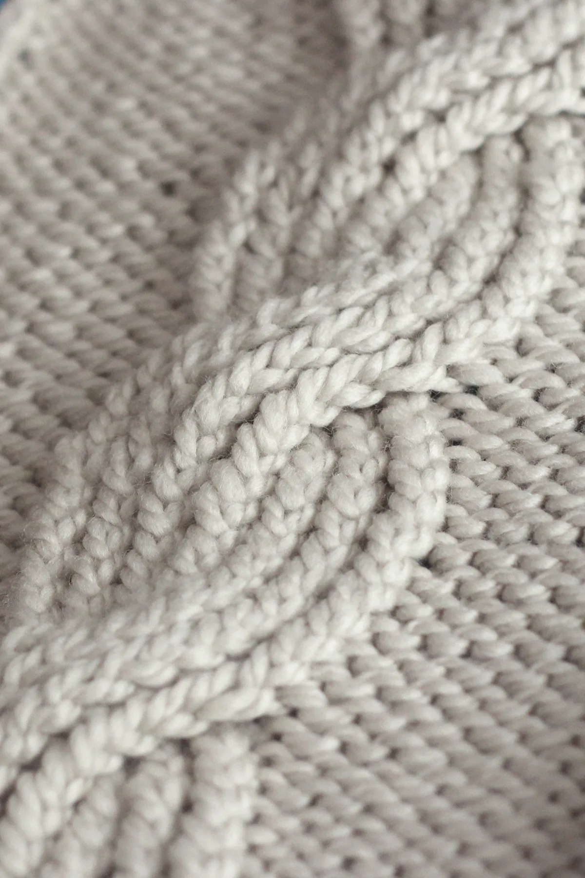 Close up of the cable braid in the Seven Seas knit stitch pattern in beige colored yarn.