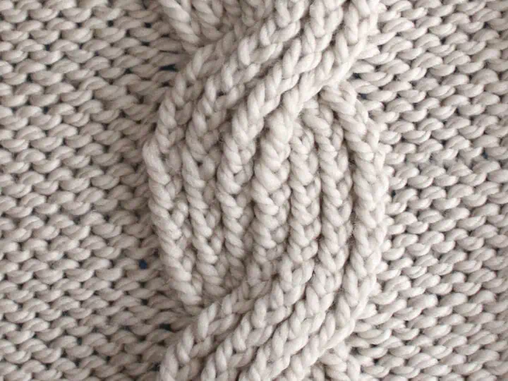 Seven seas cable ribbing knit stitch pattern in beige colored yarn.