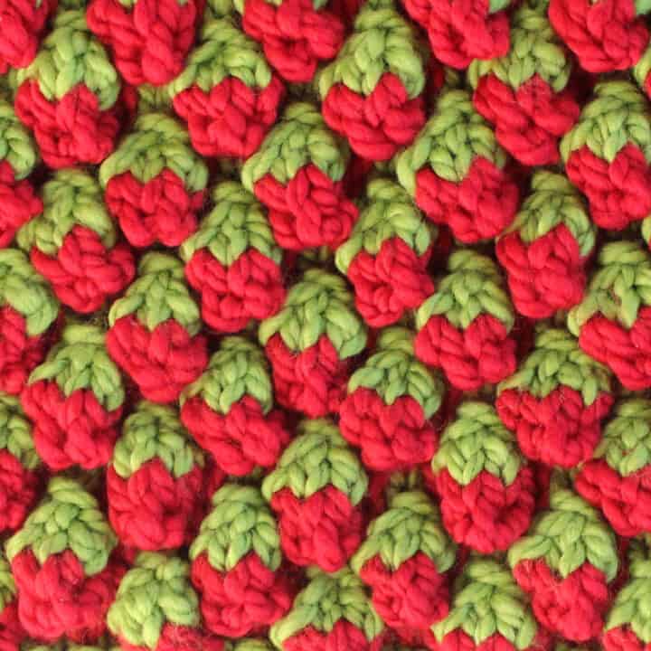 Strawberry knit stitch bobble pattern in red and green colored yarn.