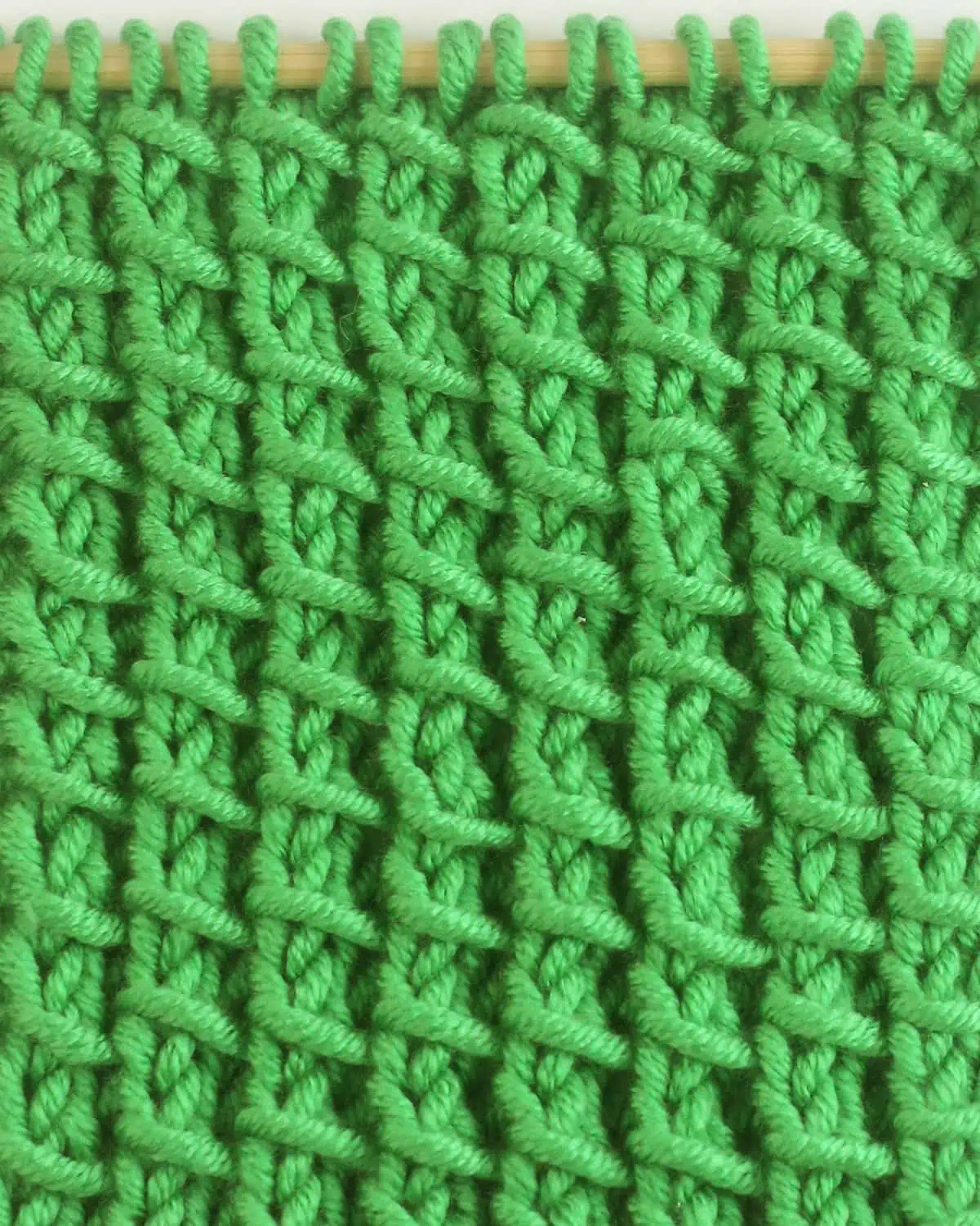 Bamboo Stitch texture knitted with green colored yarn on wooden needle.