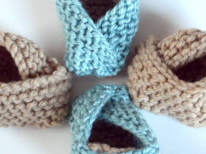 Knitted baby booties in garter stitch with beige and blue yarn colors.