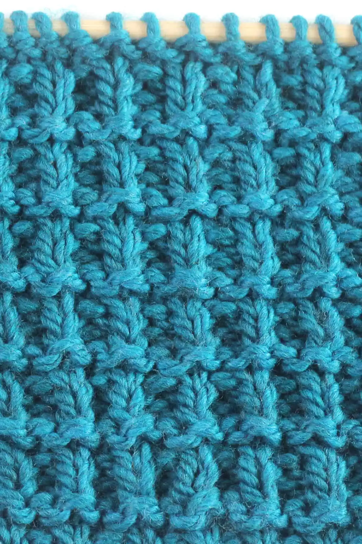 Hurdle stitch texture knitted with blue colored yarn on wooden needle.