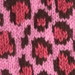 Leopard Print knit stitch stranded colorwork pattern in shades of pink and brown colored yarn on a knitting needle.