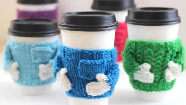 Knitted coffee mug cozies with gloved arms and a pocket.